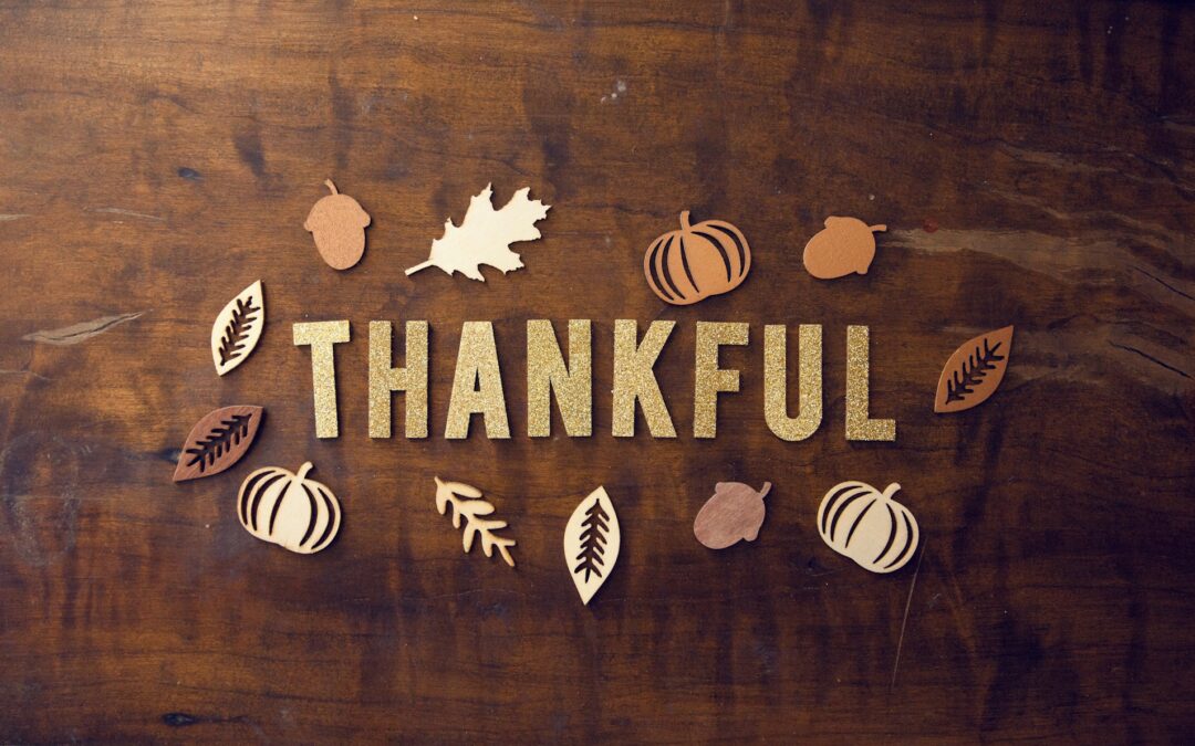 Glitter letters spelling "Thankful" on a wood table