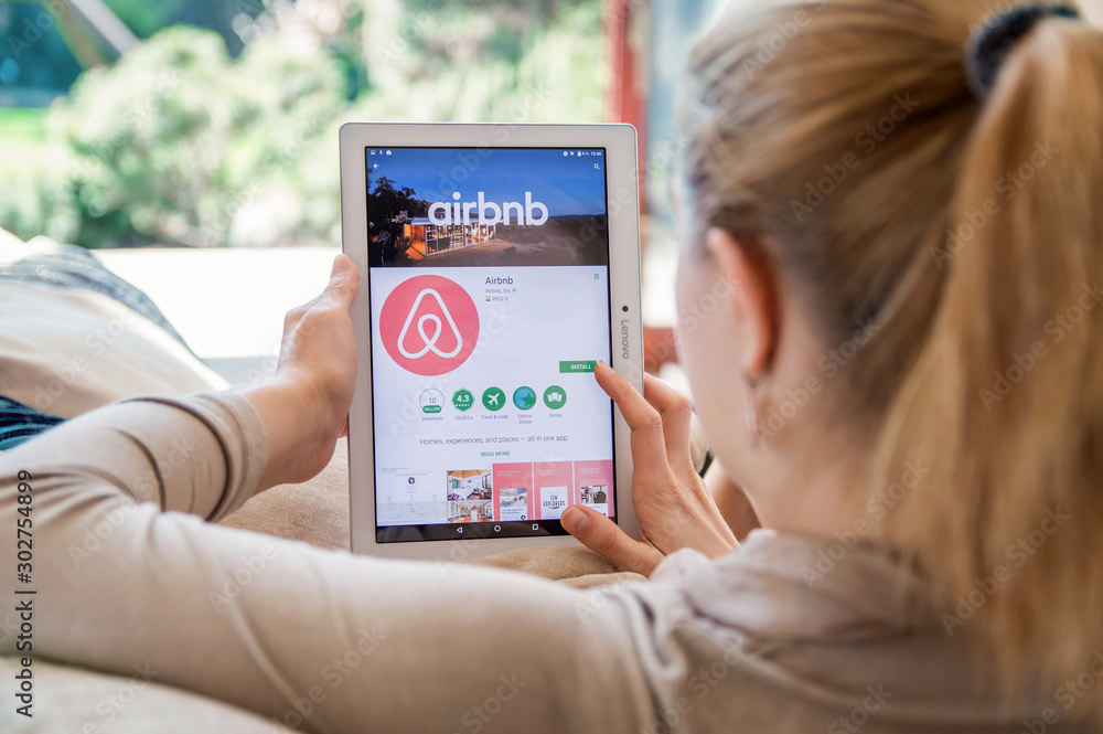 woman looking at Airbnb on tablet